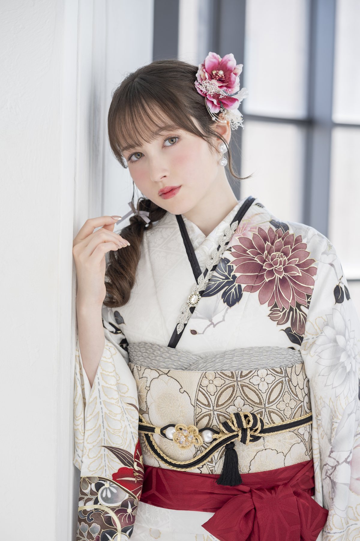 白地に花柄の振袖をまとった成人女性の立ち姿