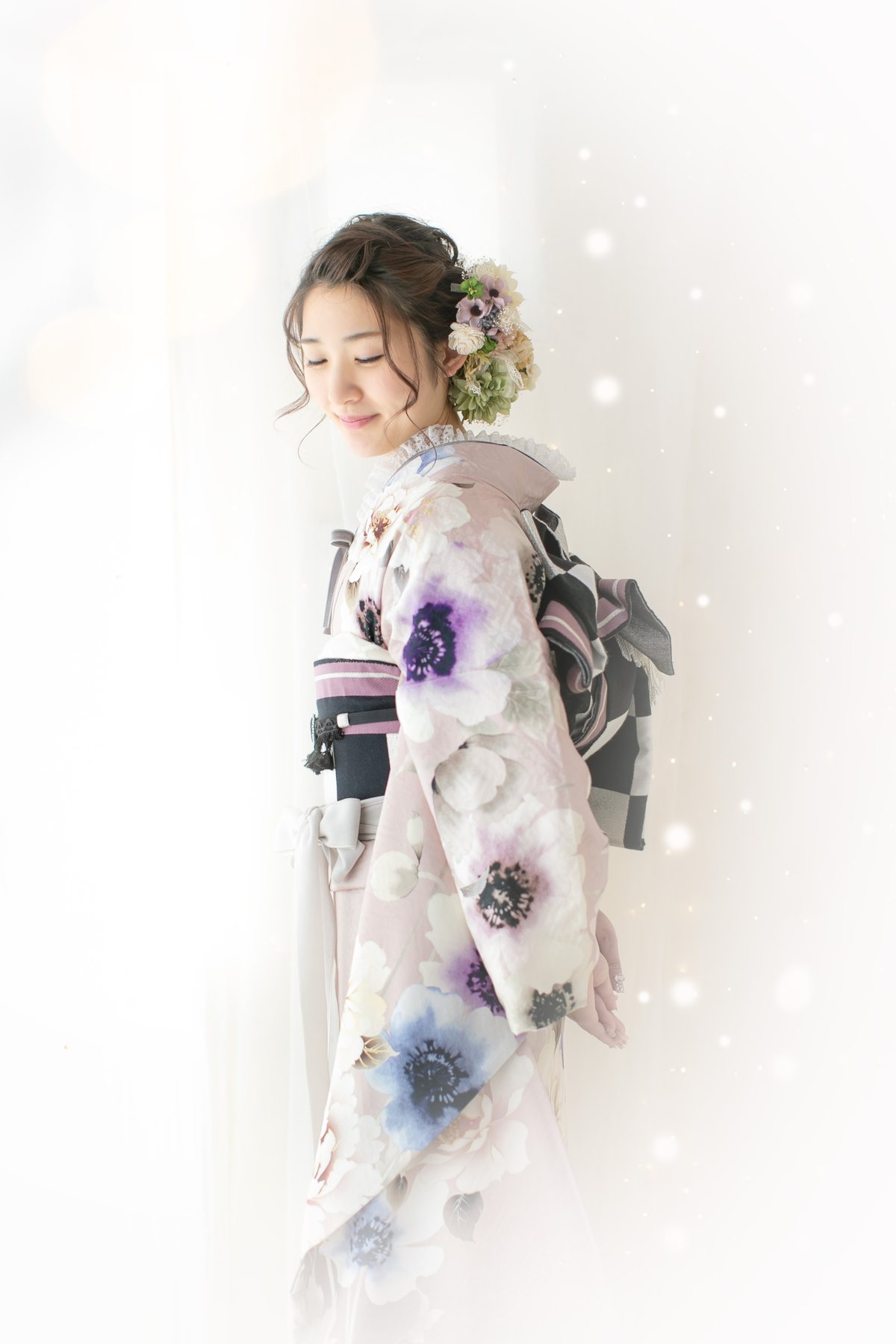 光の中で振袖の後ろ姿を見せる成人女性